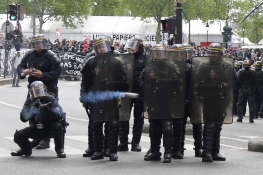 A French CRS anti-riot police officer fires a tear gas canister towards protesters during a march for the annual May Day workers' rally in Paris on May 1, 2017. / AFP PHOTO / Zakaria ABDELKAFI