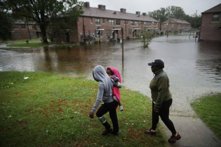 NEW BERN, NC - SEPTEMBER 13: Diamond Dillahunt, 2-year-old Ta-Layah Koonce and Shkoel Collins survey the flooding at the Trent Court public housing apartments after the Neuse River topped its banks during Hurricane Florence September 13, 2018 in New Bern, United States. Coastal cities in North Carolina, South Carolina and Virginia are under evacuation orders as the Category 2 hurricane approaches the United States. Chip Somodevilla/Getty Images/AFP