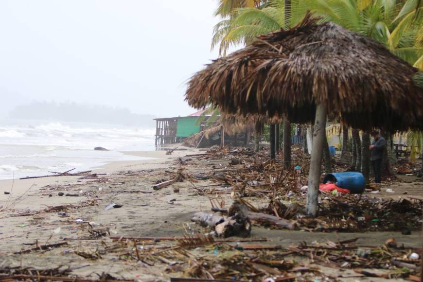 La arena blanca bañada por el mar ha sido cubierta por plásticos, barriles, restos de palmas y troncos que han sido arrastrados por el mar.