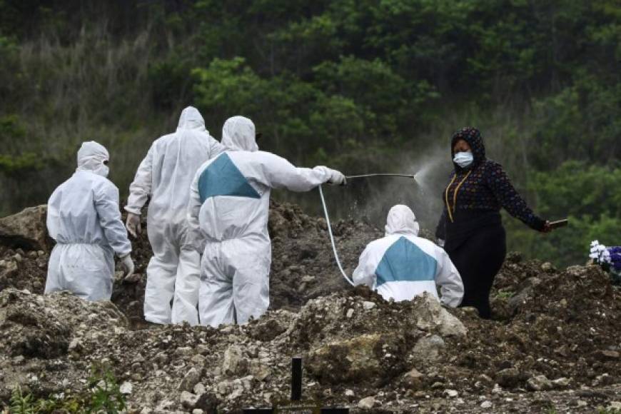 Los sepultureos visten trajes de bioseguridad y después del entierro se desinfectan. También desinfectan a los familiares de los fallecidos antes de abandonar el cementerio.