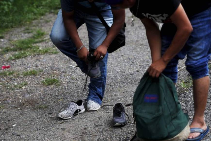 Tras varios días caminando, migrantes hondureños cambian sus zapatos desgastados para seguir su trayecto hacia México.