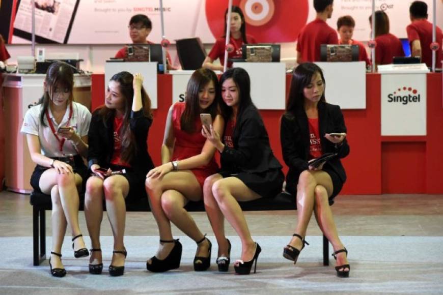 Jóvenes impulsadoras se divierten con sus iPhones en Singapur.