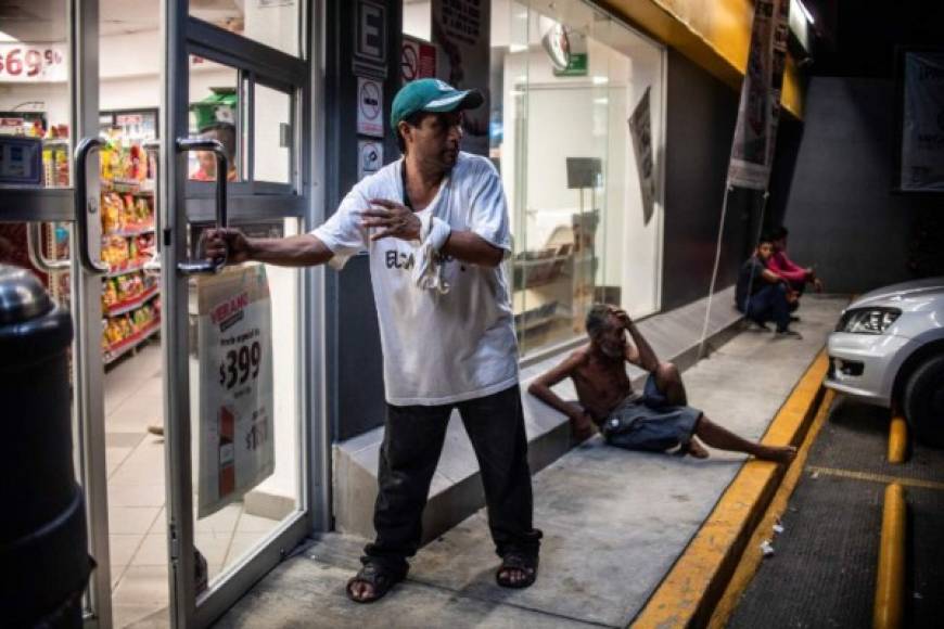En la ruta, los migrantes hacen cualquier tipo de trabajo para ganarse unos pesos para comprar alimentos, como este salvadoreño que abre la puerta de una tienda a los clientes para pedir propina.