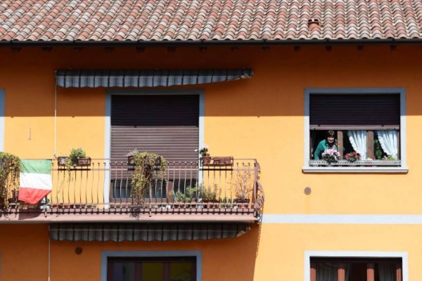 Detrás de él, las banderas italianas ondean en los balcones, al lado de sábanas y carteles decorados con los colores del arcoiris por niños.<br/><br/>'Andra tutto bene', 'Todo saldrá bien', reza uno de ellos, una de las consignas nacionales.