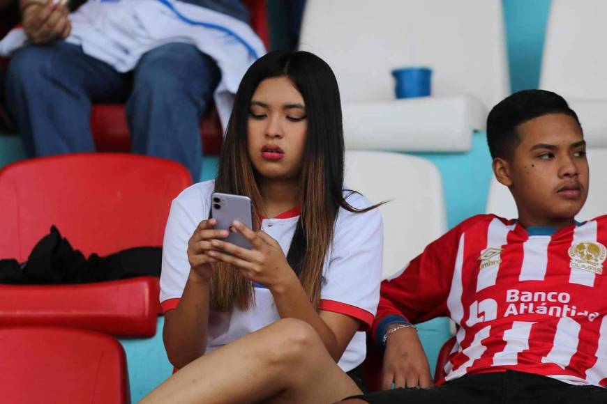 Esta aficionada se entretuvo con su celular antes del inicio del partido.