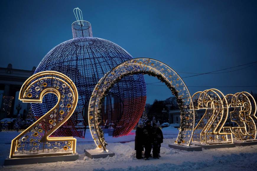 A family poses for a picture in front of Christmas and New Year decorations in Moscow on December 19, 2022. (Photo by Natalia KOLESNIKOVA / AFP)