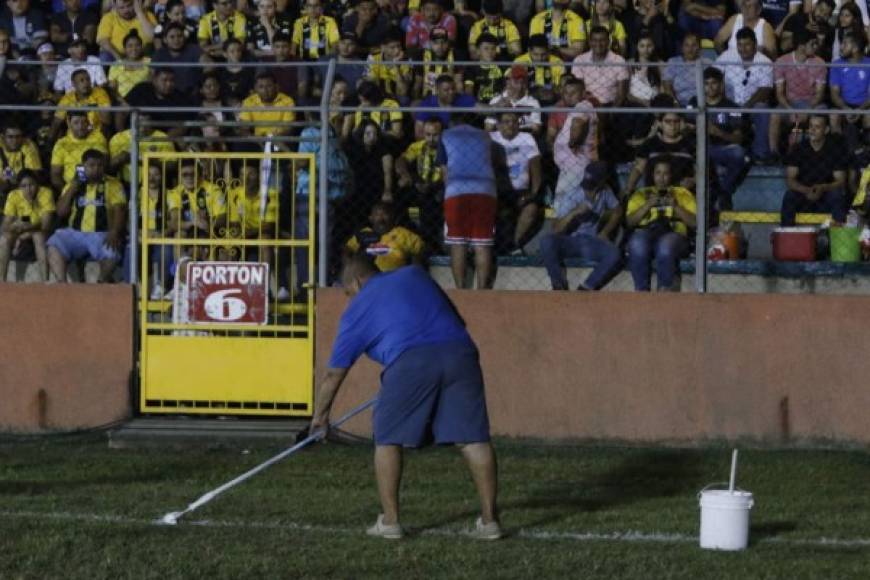 Un empleado del estadio Micheletti pintando las líneas del lado de la cancha donde estaba oscuro por falta de luz.