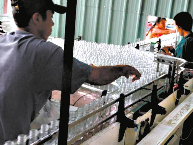 <b><span class=mln_uppercase_mln>Labor.</span></b> Un empleado revisabotellas de bebidas.