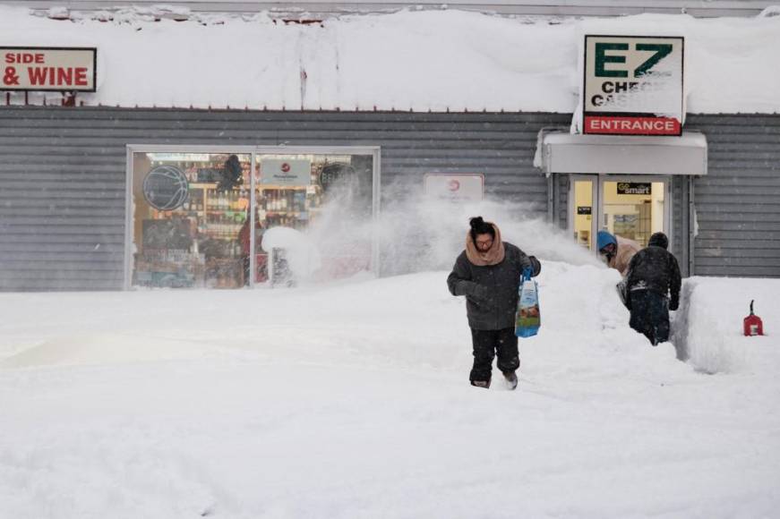 A resident leaves a local corner store in Buffalo, New York, on December 26, 2022, as many major grocery stores remained closed. - Emergency crews in New York were scrambling on December 26, 2022, to rescue marooned residents from what authorities called the "blizzard of the century," a relentless storm that has left at least 25 dead in the state and is causing US Christmas travel chaos. (Photo by Joed Viera / AFP)