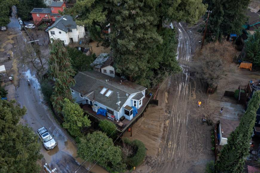 In this aerial picture taken on January 14, 2023, residents clean up their muddy neighborhood in Felton, California, as a series of atmospheric river storms continues to cause widespread destruction across the state. - The latest in a damaging succession of storm systems blew into California on Saturday, bringing heavy flooding to already waterlogged regions and threatening snowfalls of up to six feet (two meters) in areas. (Photo by DAVID MCNEW / AFP)