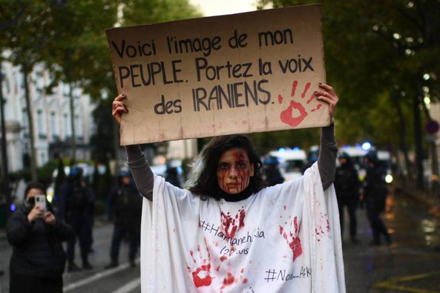 Uns manifestante sostiene una pancarta que dice ‘Esta es la imagen de mi pueblo. La joven se para frente a la policía antidisturbios durante una manifestación en apoyo de los manifestantes iraníes que se desarroló también en París, Francia.