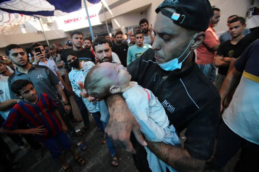 Un hombre carga a un bebé en brazos cuando llega al hospital Al-Shifa tras el bombardeo israelí del barrio Mansura de la ciudad de Gaza.