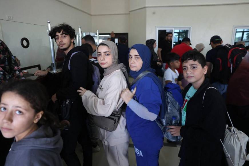  Civiles que salen de Gaza esperan mientras palestinos y extranjeros con doble nacionalidad se preparan para cruzar el punto fronterizo sur de Rafah con Egipto, en el sur de la Franja de Gaza