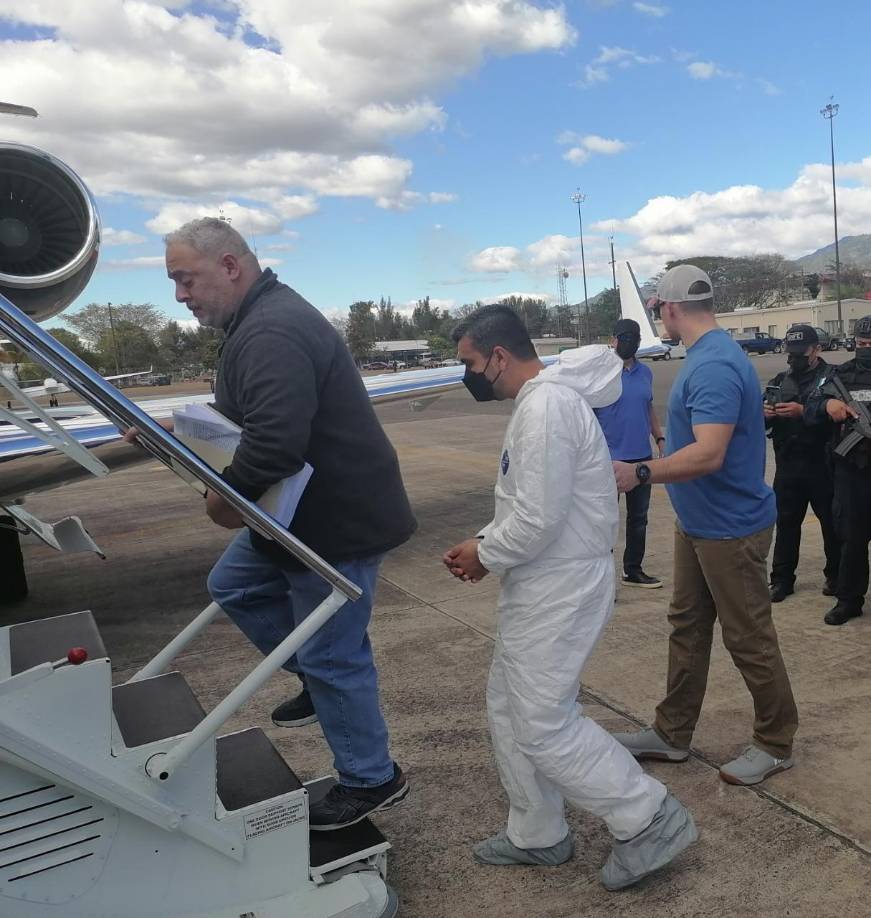 El supuesto narcotraficante, esposado de manos, subió al avión del sistema de justicia de EE.UU. vestido con un traje de bioseguridad de color blanco, afirmó a periodistas el director de Prevención y Seguridad Comunitaria, Miguel Pérez Suazo.