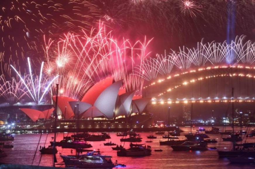 New Year's Eve fireworks erupt over Sydney's iconic Harbour Bridge and Opera House (L) during the fireworks show on January 1, 2020. (Photo by PETER PARKS / AFP)