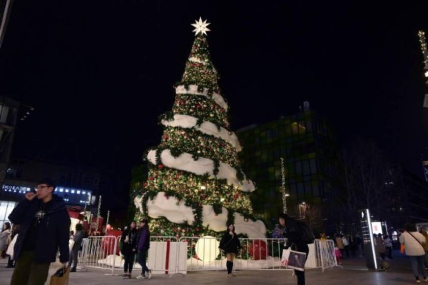 Personas posan para una foto junto a un árbol de Navidad en China.