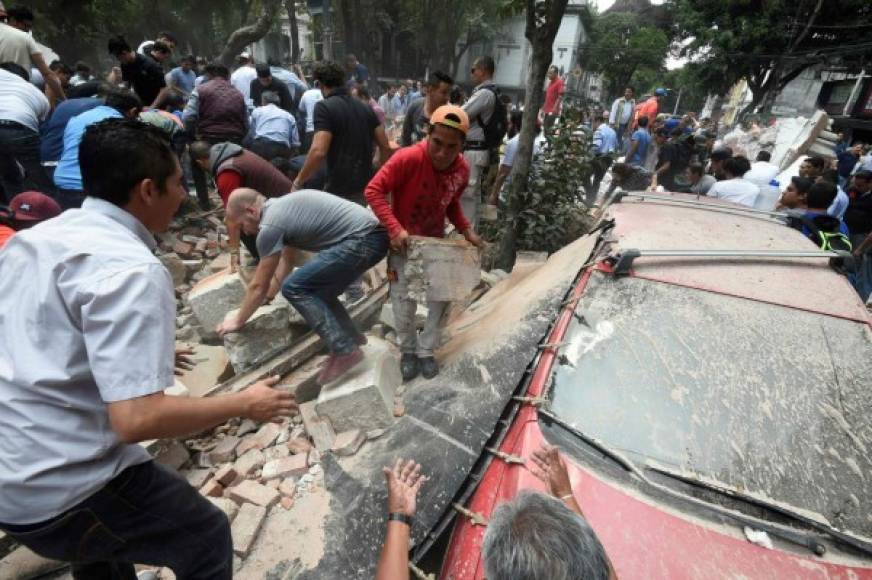 People remove debris of a building which collapsed after a quake rattled Mexico City on September 19, 2017.<br/>A powerful earthquake shook Mexico City on Tuesday, causing panic among the megalopolis' 20 million inhabitants on the 32nd anniversary of a devastating 1985 quake. The US Geological Survey put the quake's magnitude at 7.1 while Mexico's Seismological Institute said it measured 6.8 on its scale. The institute said the quake's epicenter was seven kilometers west of Chiautla de Tapia, in the neighboring state of Puebla.<br/> / AFP PHOTO / Alfredo ESTRELLA