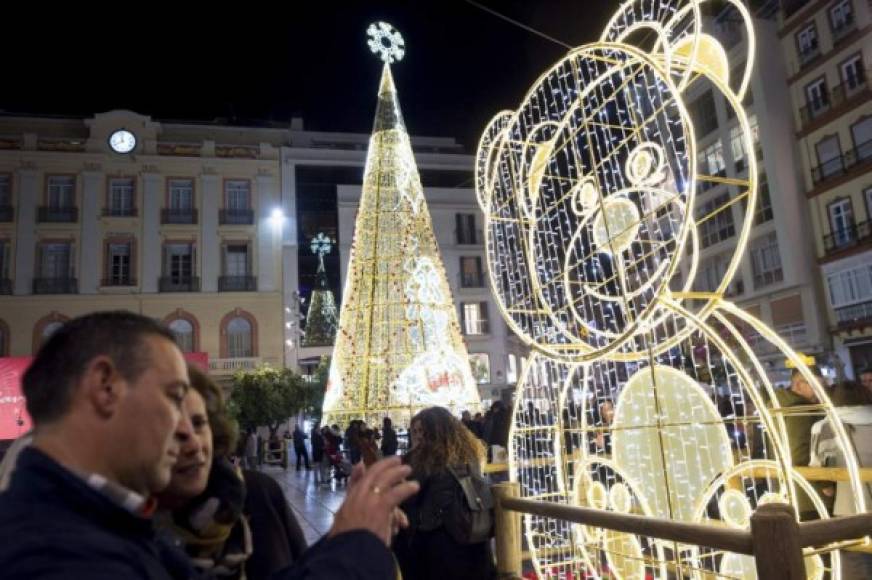 La gente camina en la plaza de la Constitución adornada con un árbol de Navidad y luces en Málaga.