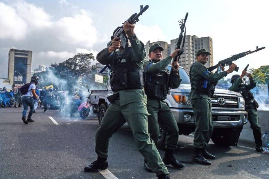 Members of the Bolivarian National Guard who joined Venezuelan opposition leader and self-proclaimed acting president Juan Guaido fire into the air to repel forces loyal to President Nicolas Maduro who arrived to disperse a demonstration near La Carlota military base in Caracas on April 30, 2019. - Guaido -- accused by the government of attempting a coup Tuesday -- said there was 'no turning back' in his attempt to oust President Nicolas Maduro from power. (Photo by Federico PARRA / AFP)