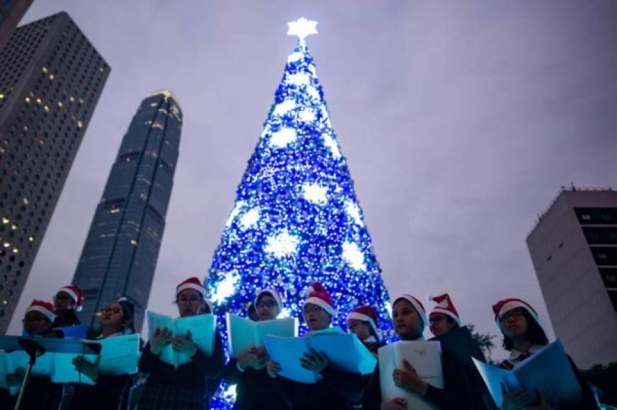 Un coro de escuela primaria canta villancicos debajo de un árbol de Navidad en el distrito Central de Hong Kong.
