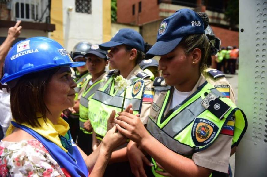 Una activista le entrega una rosa blanca a una oficial de la Policía Nacional Bolivariana.
