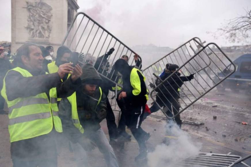Demonstrators throws metal barriers during a protest of Yellow vests (Gilets jaunes) against rising oil prices and living costs, on the Champs Elysees avenue in Paris on December 1, 2018. - Thousands of anti-government protesters are expected today on the Champs-Elysees in Paris, a week after a violent demonstration on the famed avenue was marked by burning barricades and rampant vandalism that President Emmanuel Macron compared to 'war scenes'. (Photo by Lucas BARIOULET / AFP)