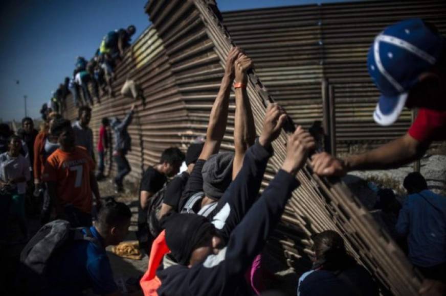 A group of Central American migrants -mostly Hondurans- climb the border fence between Mexico and the United States as others try to bring it down, near El Chaparral border crossing, in Tijuana, Baja California State, Mexico, on November 25, 2018. - Hundreds of migrants attempted to storm a border fence separating Mexico from the US on Sunday amid mounting fears they will be kept in Mexico while their applications for a asylum are processed. An AFP photographer said the migrants broke away from a peaceful march at a border bridge and tried to climb over a metal border barrier in the attempt to enter the United States. (Photo by Pedro PARDO / AFP)