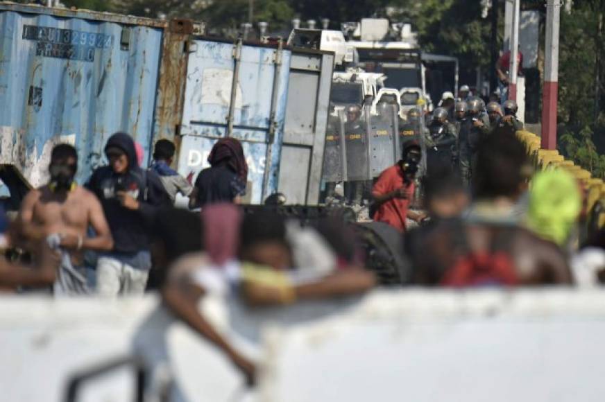 Demonstrators confront Venezuelan security forces in San Antonio del Tachira, Venezuela, as seen from across the Simon Bolivar International Bridge in Cucuta, Colombia, on February 25, 2019. - United States Vice President Mike Pence told Venezuelan opposition leader Juan Guaido that Donald Trump supports him '100 percent' as the pair met regional allies on Monday to thrash out a strategy to remove Nicolas Maduro from power after the failed attempt to ship in humanitarian aid. (Photo by Luis ROBAYO / AFP)