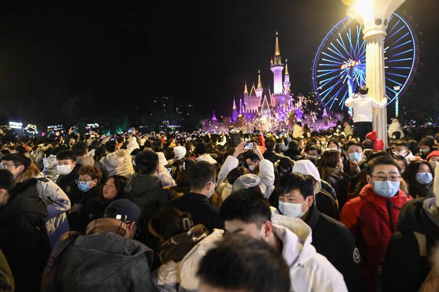 Personas que usan máscaras asisten a la cuenta regresiva de Año Nuevo en un parque de diversiones en Beijing el 1 de enero de 2022.