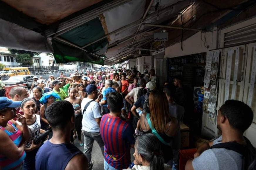 Decenas de personas también se aglomeran en uno de los pocos mercados abiertos en Caracas, que funciona a medias por los cortes de luz.