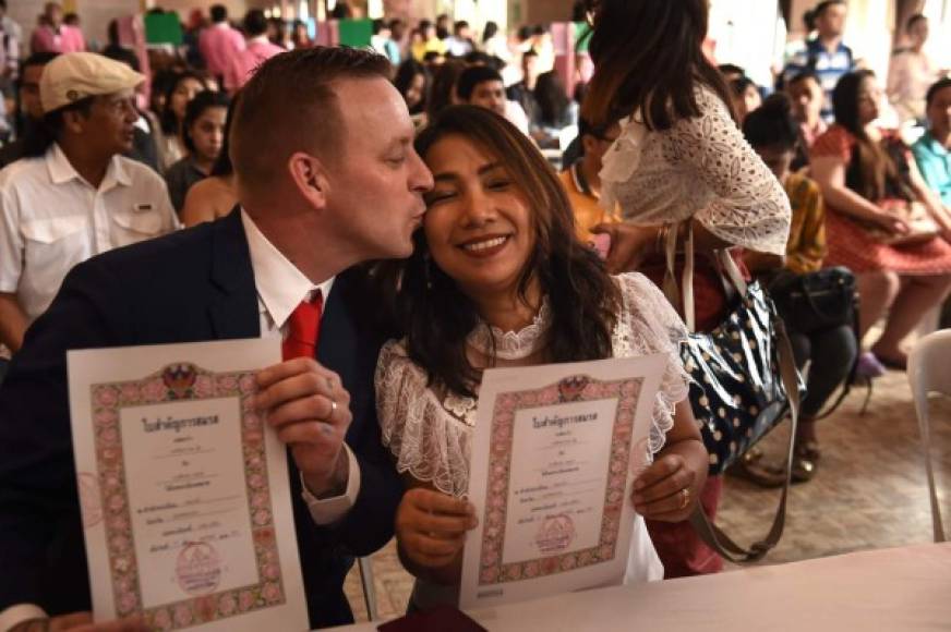 Una pareja británica posa con su licencia matrimonial en Tailandia.