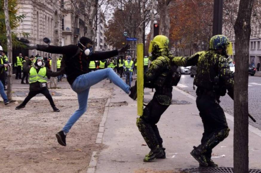 A demonstrator clashes with riot police during a protest of Yellow Vests (Gilets jaunes) against rising oil prices and living costs on the Champs Elysees in Paris, on December 1, 2018. (Photo by ALAIN JOCARD / AFP)