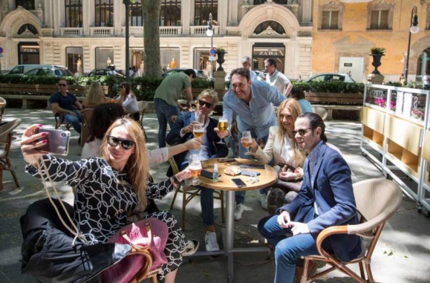 People take a selfie as they share a toast at a terrace bar in Palma de Mallorca on May 11, 2020, as Spain moved towards easing its strict lockdown in certain regions. - Spaniards returned to outdoor terraces at cafes and bars as around half of the country moved to the next phase of a gradual exit from one of Europe's strictest lockdowns (Photo by JAIME REINA / AFP)