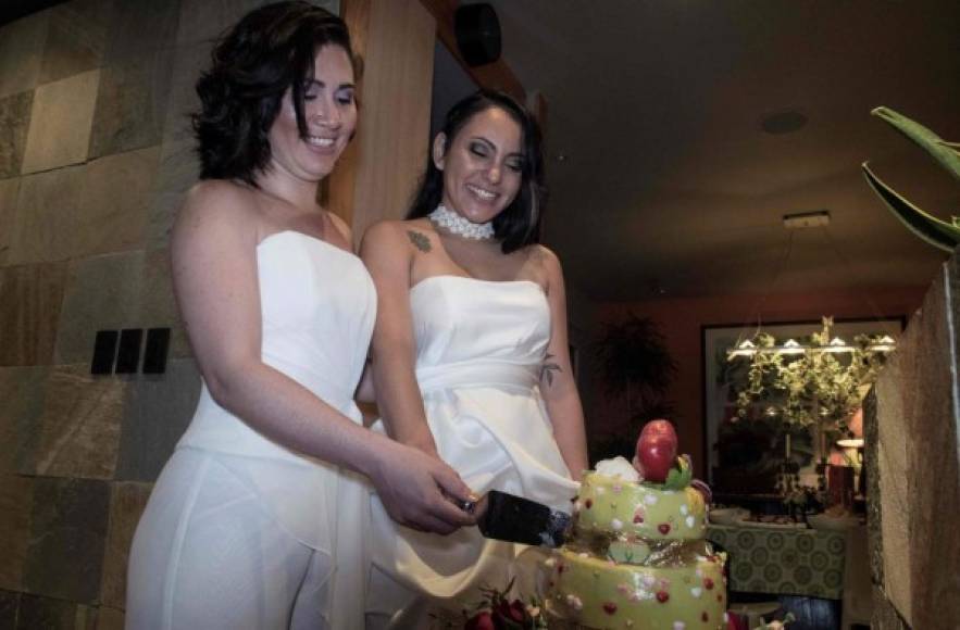Same-sex newlyweds Alexandra Quiros (L) and Dunia Araya (R) cut a cake during their wedding in Heredia, Costa Rica, on May 26, 2020. - Costa Rica legalised same-sex marriage on May 26, becoming the first Central American country to do so and sparking an emotional response from rights campaigners as the first weddings were held overnight. (Photo by Ezequiel BECERRA / AFP)