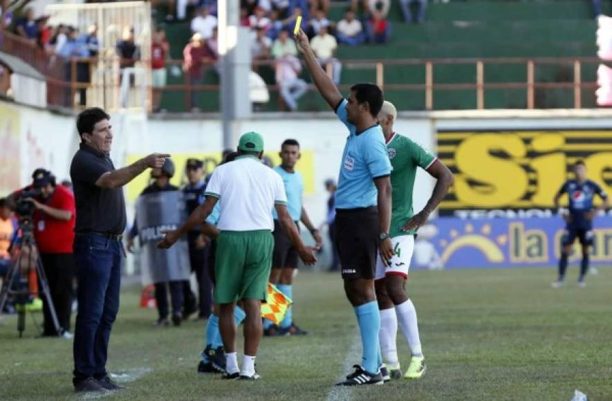 El árbitro Raúl Castro le muestra la tarjeta amarilla a Héctor Vargas, técnico del Marathón.