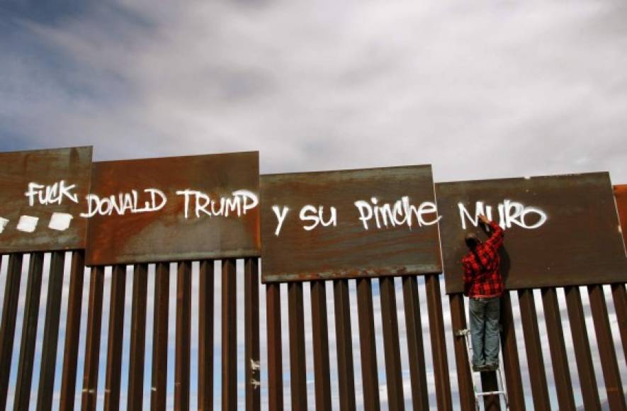 An activist paints the wall between the United States and Mexico during a demonstration against US President Donald Trump on the border of Ciudad Juarez with Nuevo Mexico, Chihuahua State, Mexico on February 26, 2017. / AFP PHOTO / HERIKA MARTINEZ