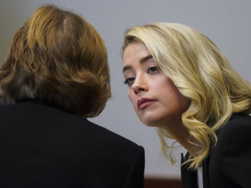 La actriz Amber Heard habla con su abogada Elaine Bredehoft durante el juicio por difamación interpuesto por su exesposo.