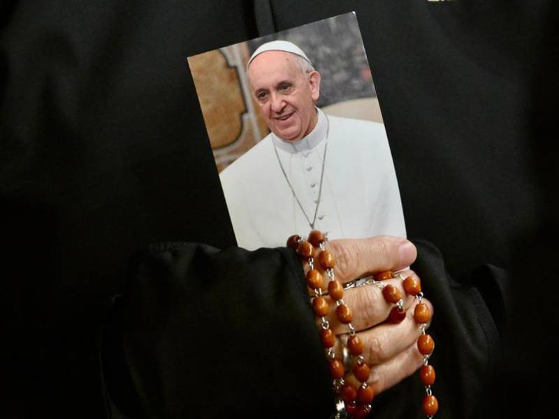 Una monja sostiene una imagen del Papa Francisco y un rosario mientras los fieles asisten a una oración del Rosario por la salud del pontífice en la Plaza de San Pedro .