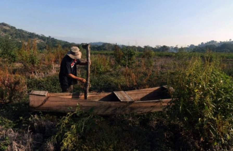 Un pescador observa el bote de madera que usaba para pescar y que permanece varado en las lagunas secas de Jucutuma. AFP