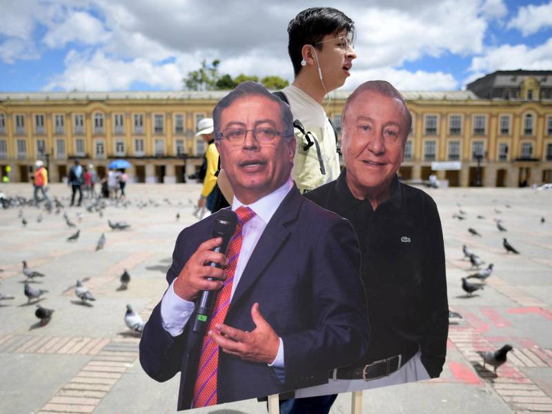 Un hombre sostiene carteles de cartón con imágenes del candidato presidencial de izquierda, Gustavo Petro, y el candidato presidencial por el partido ‘Liga de Gobernantes Anticorrupción’, Rodolfo Hernández.