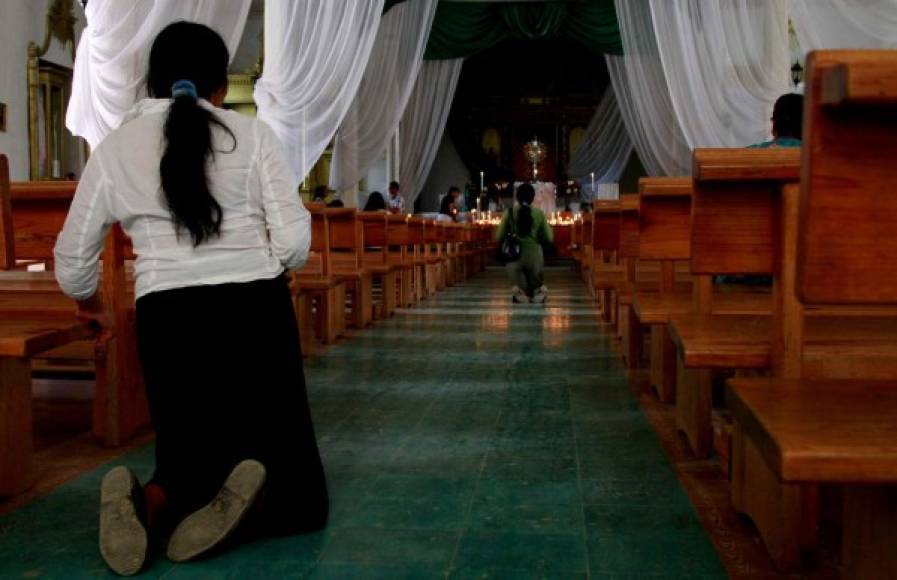 Imagen de una mujer cumpliendo una petición en una iglesia hondureña.
