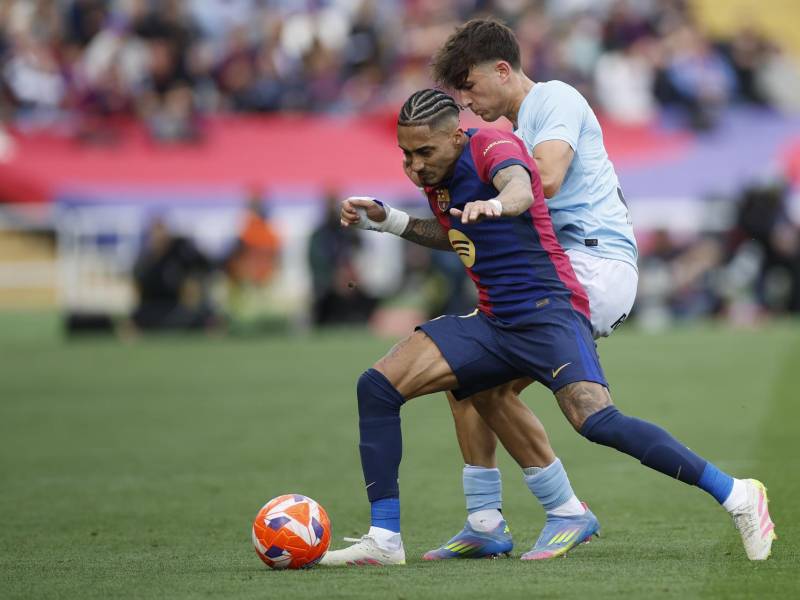El delantero del FC Barcelona Raphael Dias Belloli Raphinha (i) y el central derecho del Celta de Vigo Javi Rodríguez pelean por el balón durante el partido de la jornada 32 de LaLiga EA Sports que FC Barcelona y Celta de Vigo disputan este sábado en el estadio olímpico Lluís Companys en Barcelona.