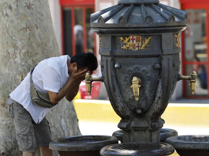 Un hombre se refresca en una fuente ante las altas temperaturas por la ola de calor que golpea España.