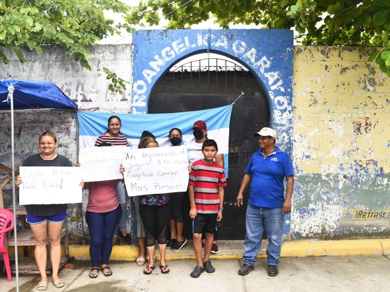 Padres mantienen la Bandera Nacional en la entrada de la escuela en señal de protesta