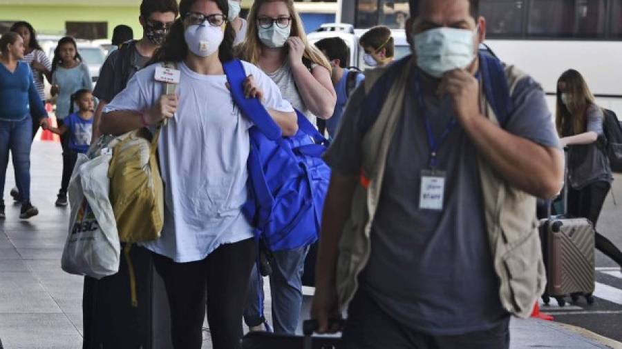 $!Passengers wear protective face masks to prevent the spread of the new Coronavirus, COVID-19, outside the Toncontin International Airport, in Tegucigalpa, on March 14, 2020. - Honduran government has prohibited citizens from Europe, China, Iran, and South Korea the entrance to the country. (Photo by ORLANDO SIERRA / AFP)