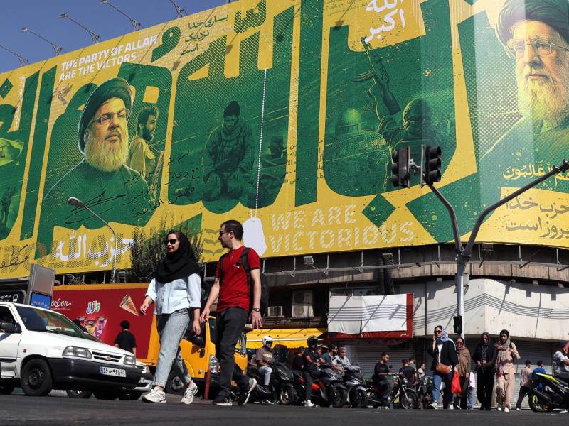 Iraníes transitan ante una valla publicitaria en Teherán que representa al exlíder de Hizbulá, Hasán Nasrala (i) y al difunto líder supremo iraní, Alí Jameneí (d). EFE/EPA/ABEDIN