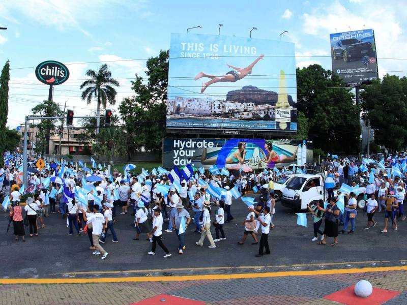 Personas participan en una marcha por la paz este sábado, en San Pedro Sula.