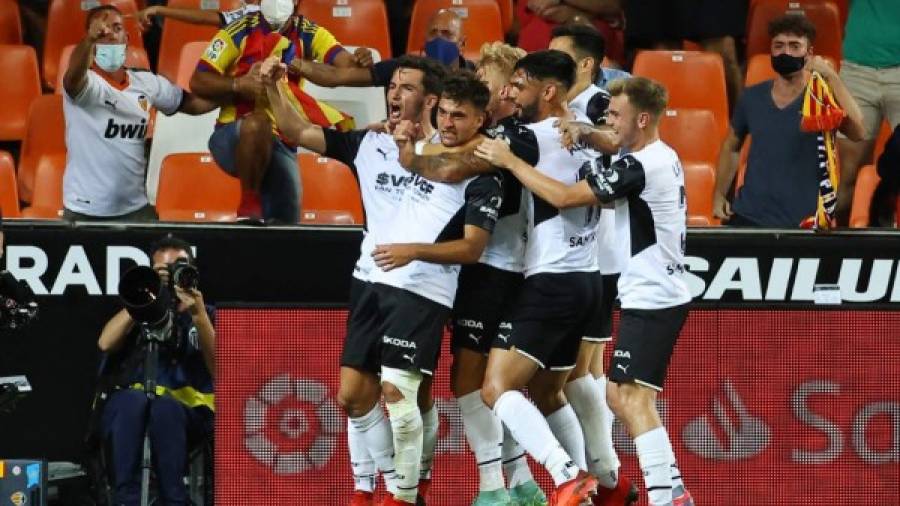 $!Valencia players celebrate the opening goal scored by Valencia's Spanish forward Hugo Duro during the Spanish League football match between Valencia CF and Real Madrid CF at the Mestalla stadium in Valencia on September 19, 2021. (Photo by JOSE JORDAN / AFP)