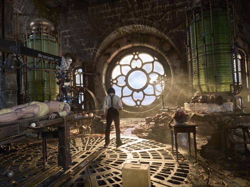 El joven actor australiano Jacob Elordi postrado como criatura en la mesa del laboratorio junto a su creador el Dr. Victor Frankenstein, que interpreta Oscar Isaac, en un momento del rodaje de la última película de Guillermo del Toro.