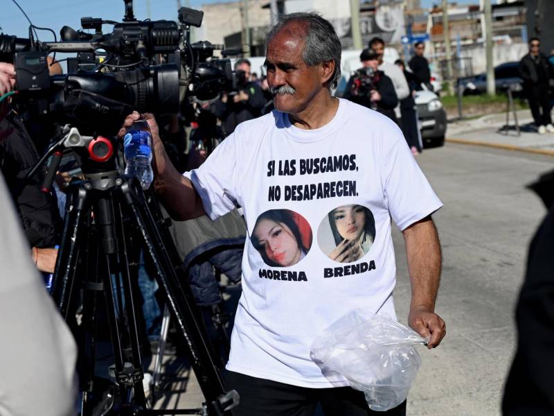 Una persona reparte agua a los periodistas, afuera del velatorio de las jóvenes asesinadas Brenda del Castillo y Morena Verdi.